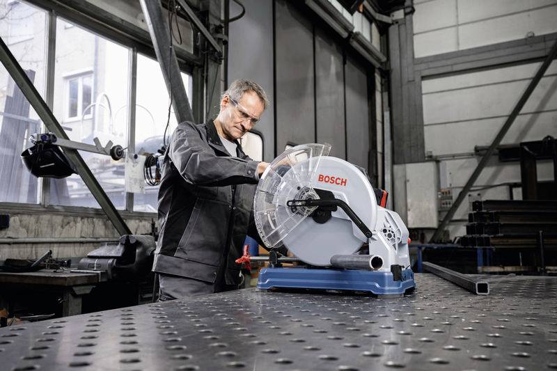 Ein Mann in Arbeitskleidung bedient eine Bosch-Maschine in einer Werkstatt. Der Raum ist industriell gestaltet mit Metallstrukturen.