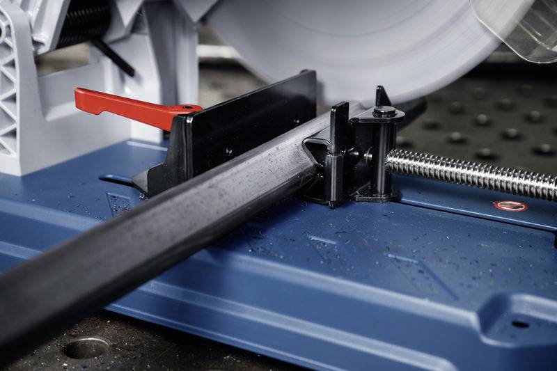 Eine Metallstange wird von einem Metallsägeblatt auf einer blauen Schneidemaschine geschnitten. Ein roter Hebel dient als Sicherung.