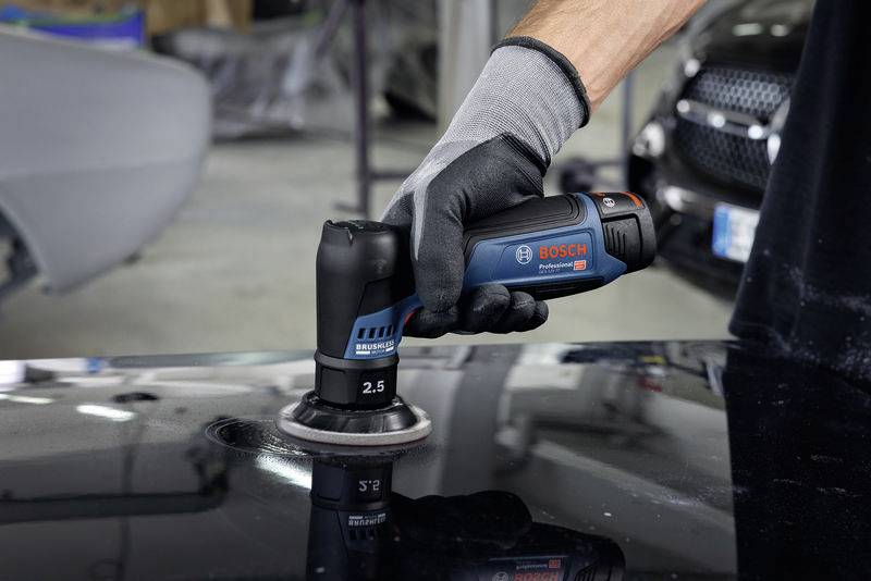 Eine Person benutzt ein Bosch-Poliergerät auf einer dunklen Oberfläche. Im Hintergrund sind Autos sichtbar.