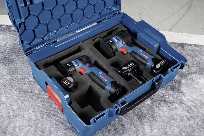 Blauer Werkzeugkoffer mit zwei Akku-Bohrschraubern, zwei Akkus und einem Ladegerät in schwarzer, geformter Einlage.