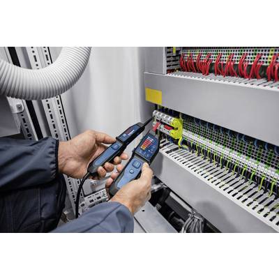 Eine Person testet elektrische Verbindungen in einem Schaltschrank mit einem digitalen Prüfgerät.
