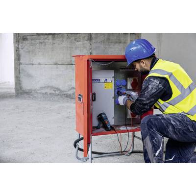 Ein Arbeiter mit blauer Schutzkappe und Warnweste überprüft ein elektrisches Schaltschrankgehäuse auf einer Baustelle.