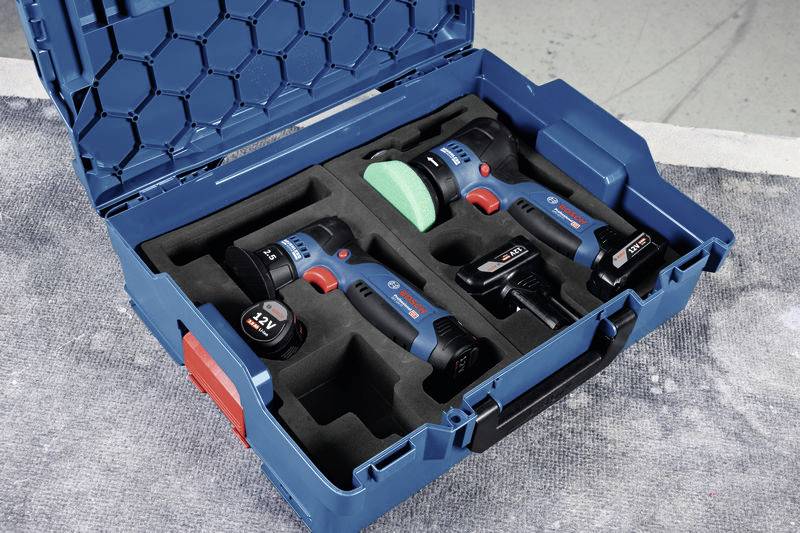 Ein offenes, blaues Werkzeugkoffer-Set mit Bohrschrauber und Lampe, zwei Akkus und Ladegerät, auf grauem Untergrund.