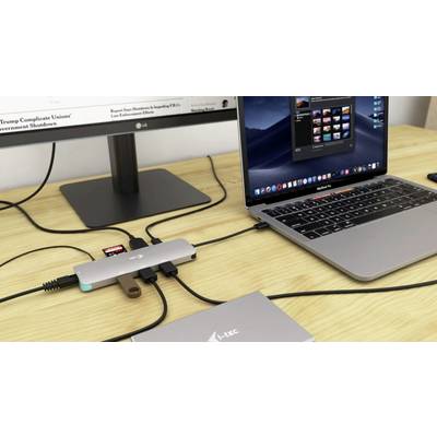 Laptop auf einem Schreibtisch mit mehreren angeschlossenen USB-Geräten und Adaptern, verbunden mit einem externen Monitor.