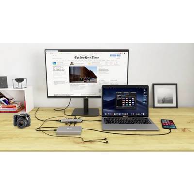Ein Schreibtisch mit einem Laptop, angeschlossen an einen Monitor, der 'The New York Times' zeigt. Daneben eine Kamera und ein Smartphone.