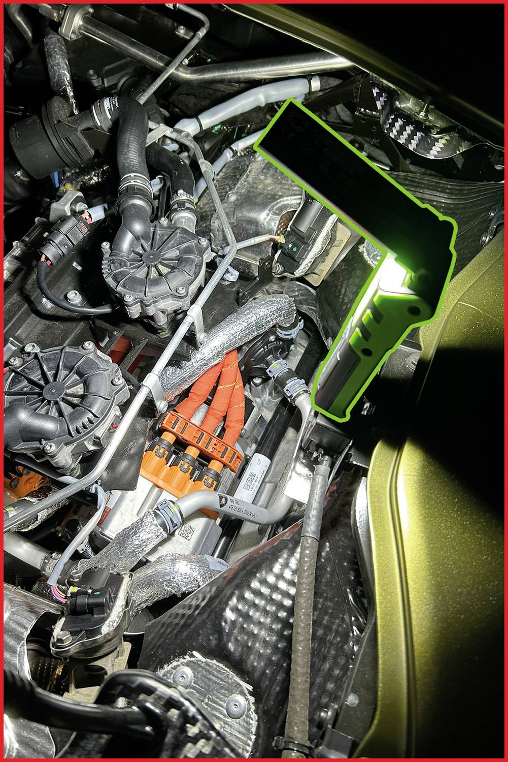 Ein hell beleuchteter Motorraum mit komplexen Kabel- und Rohrverbindungen. Eine Lampe mit grünem Rand beleuchtet den Bereich.