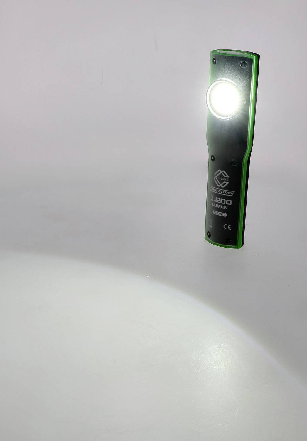 Ein tragbares, grünes LED-Licht leuchtet nach unten und erhellt den Boden in einem dunklen Raum.