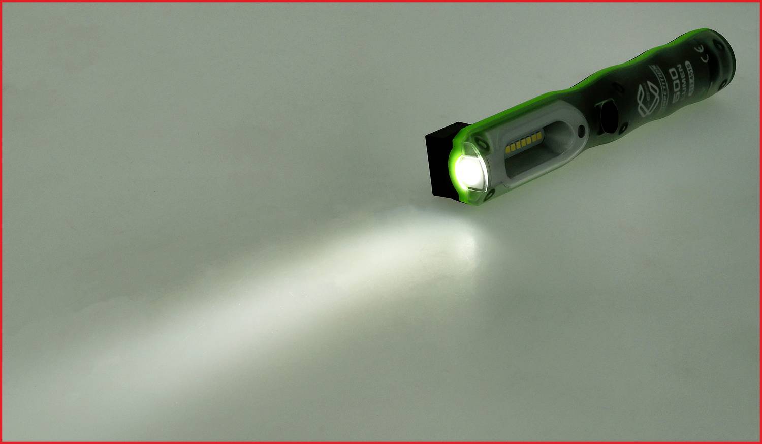 Eine grüne Taschenlampe leuchtet auf eine glatte Oberfläche, erzeugt einen engen, hellen Strahl.
