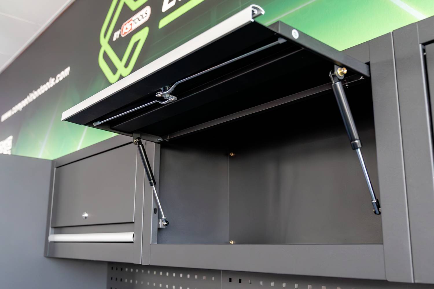 Ein Werkstatt-Aufbewahrungssystem aus Metall mit mehreren Schränken und Schubladen vor einem grünen, leuchtenden Hintergrund.