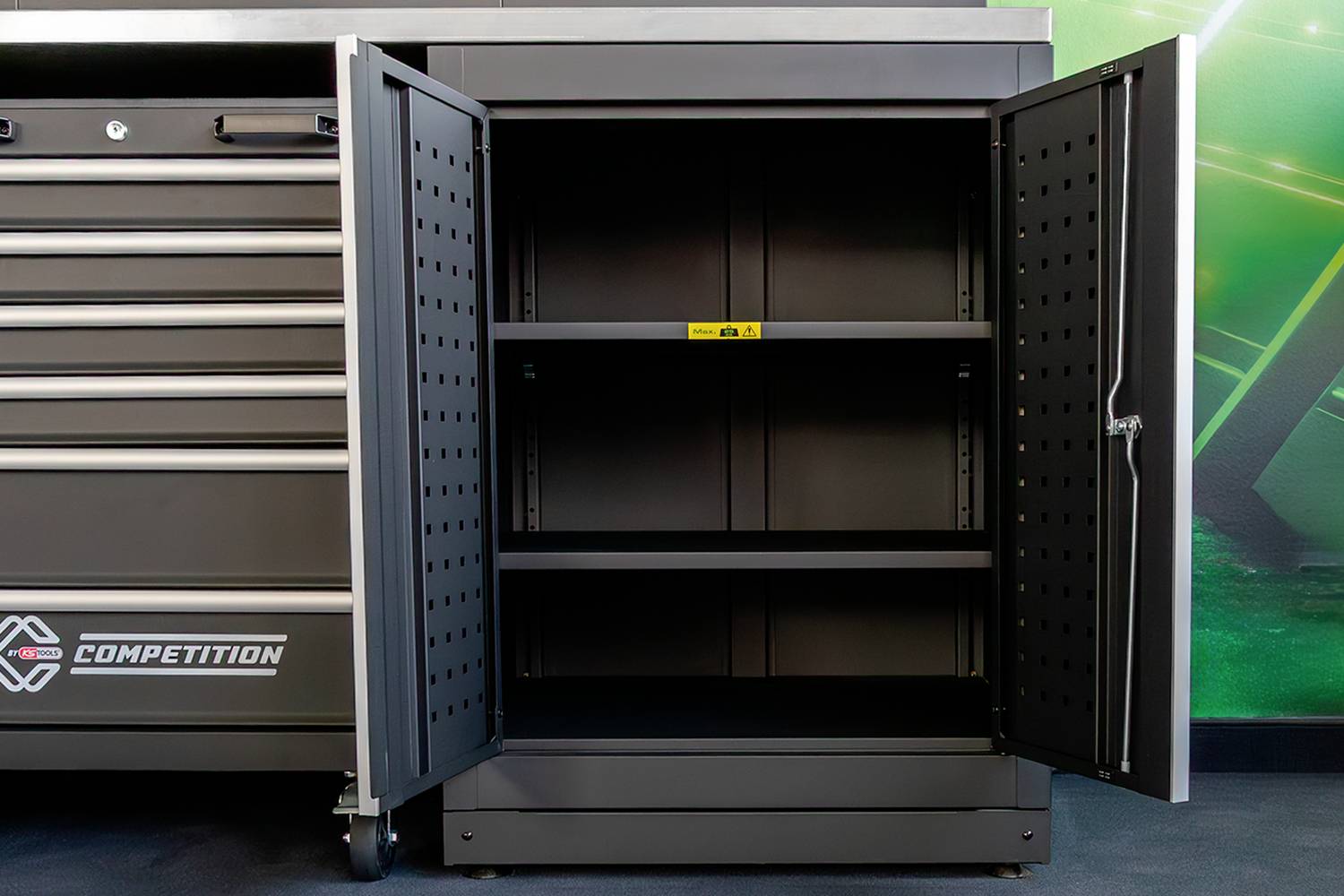 Geöffneter schwarzer Metallschrank mit zwei Regalböden, umgeben von Werkzeugschubladen.