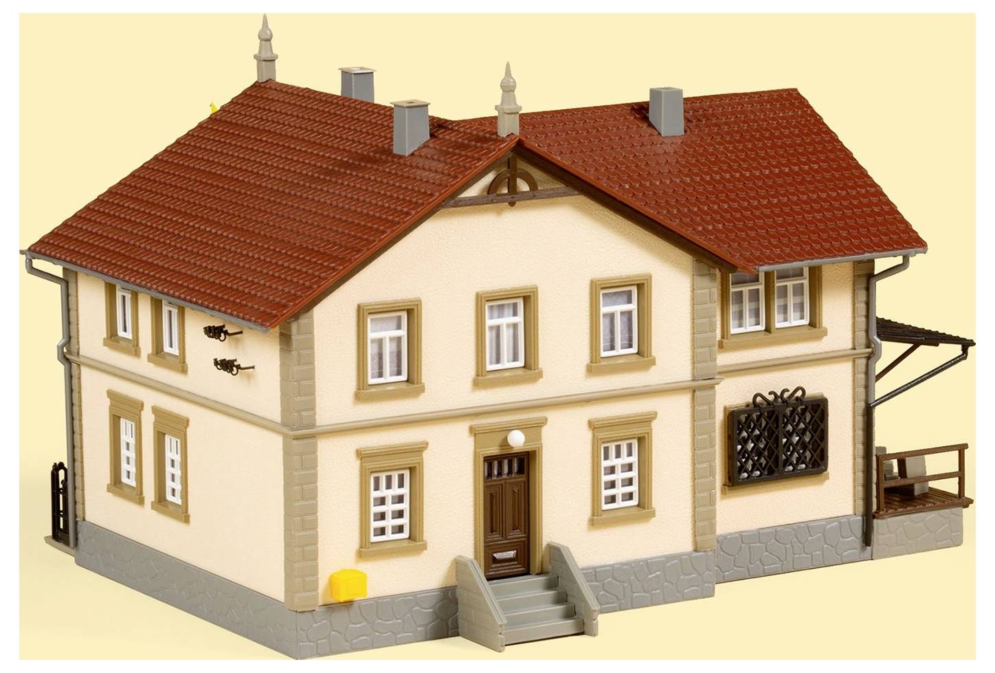 Ein Modell eines zweistöckigen Hauses mit roten Dachziegeln und cremefarbenen Wänden, Türen und Fenstern.