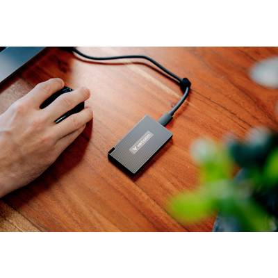 Eine Hand benutzt eine Computermaus neben einer externen Festplatte auf einem Holztisch.