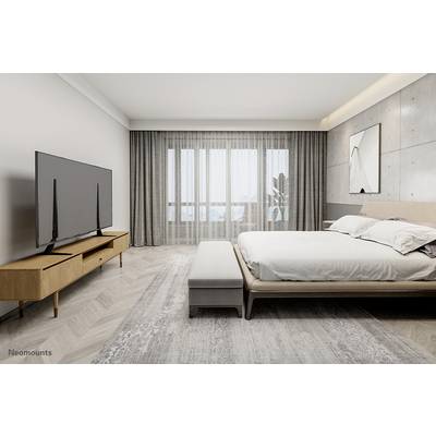 Ein modernes Schlafzimmer mit einem großen Bett, einem Holzfernsehtisch mit Flachbildfernseher und einem großen Fenster mit Vorhängen.