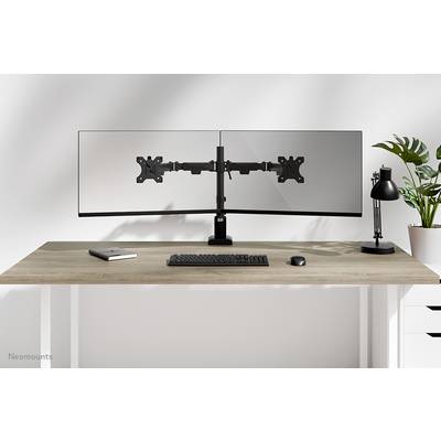 Zwei Monitore auf einem Schreibtisch mit Tastatur und Maus, links ein Notizbuch, rechts eine Lampe und Pflanzen im Hintergrund.