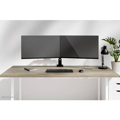 Ein moderner Schreibtisch mit zwei Monitoren, einer Tastatur, einer Maus und einer Schreibtischlampe. Daneben eine Pflanze.