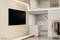 Ein modernes, minimalistisches Zimmer mit einem großen, an der Wand montierten Fernseher, einer Garderobe und schlichter Beleuchtung.