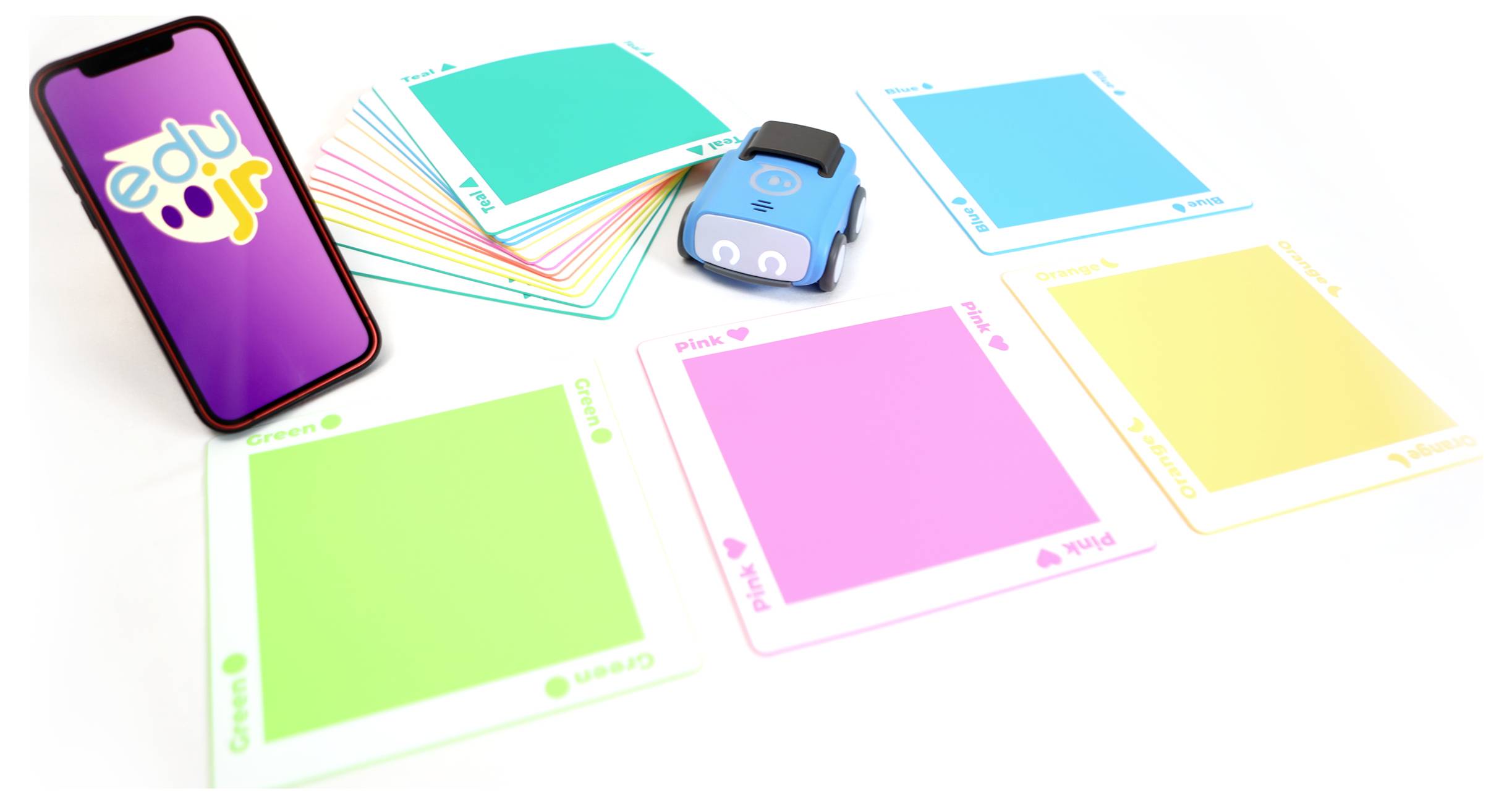 Ein Smartphone, farbige Karten und ein blaues Spielzeugauto auf einem Tisch. Die Karten sind grün, pink, gelb und blau.