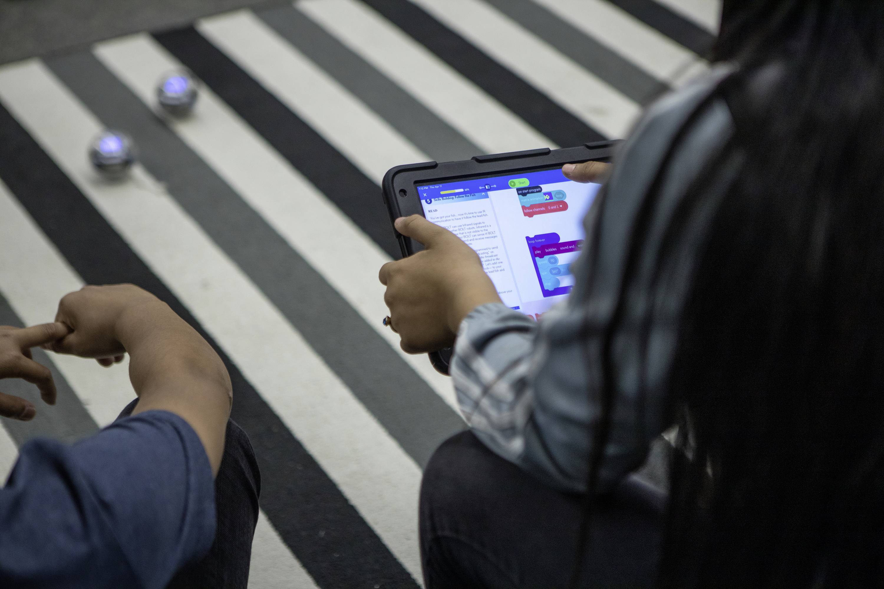 Eine Person verwendet ein Tablet, um visuelles Programmieren zu lernen. Der Bildschirm zeigt bunte Programmierblöcke in einer Lern-App.