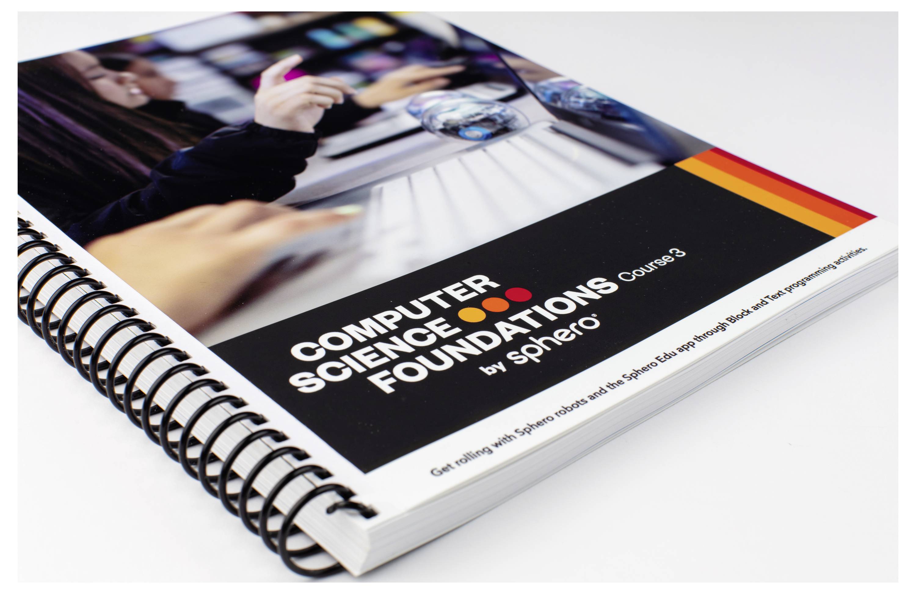 Ein Ringbuch mit dem Titel 'Computer Science Foundations Course 3 by Sphero', zeigt Hände bei der Arbeit am Computer mit Fokus auf Technologie.