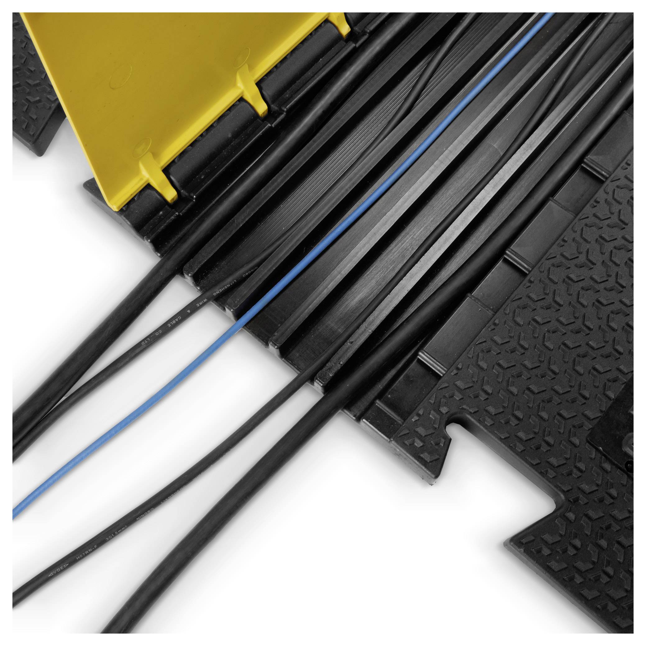 Mehrere schwarze Kabel verlaufen unter einer gelben Kabelbrücke. Die Brücke schützt und bündelt die Kabel auf einer strukturierten Oberfläche.