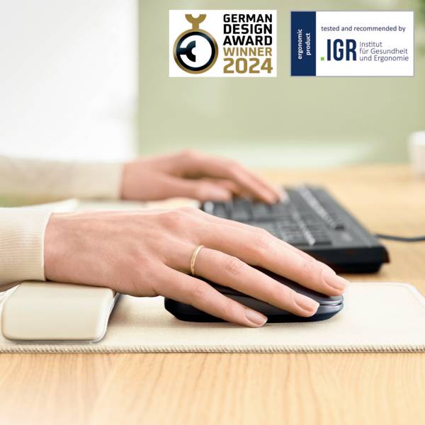 Eine Hand hält eine ergonomische Maus auf einem Handgelenkskissen. Aufkleber oben: 'German Design Award Winner 2024'.