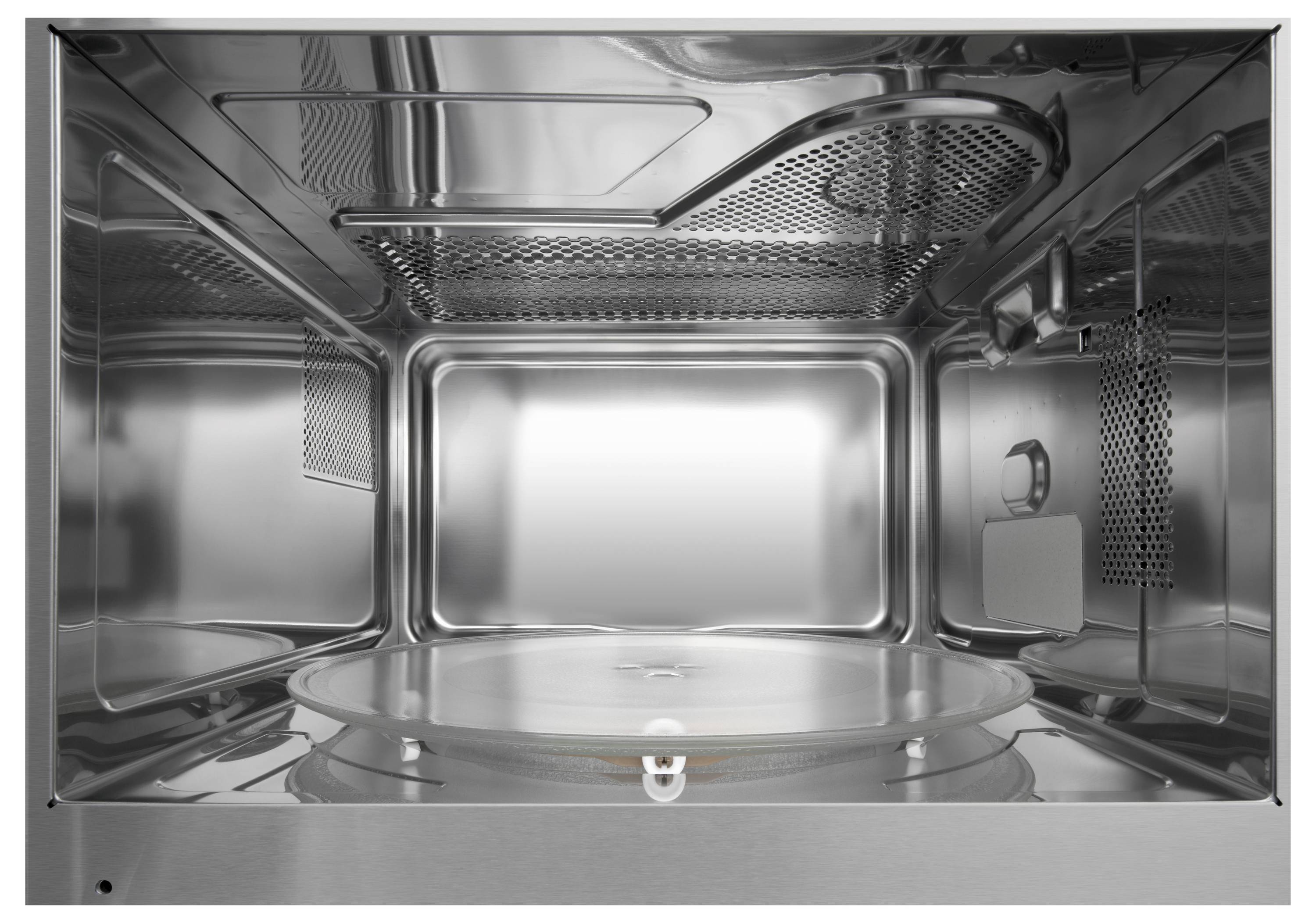 Interieur einer Mikrowelle aus Edelstahl mit Drehteller in der Mitte. Reflektierende Wände und Decke mit Belüftungsschlitzen.
