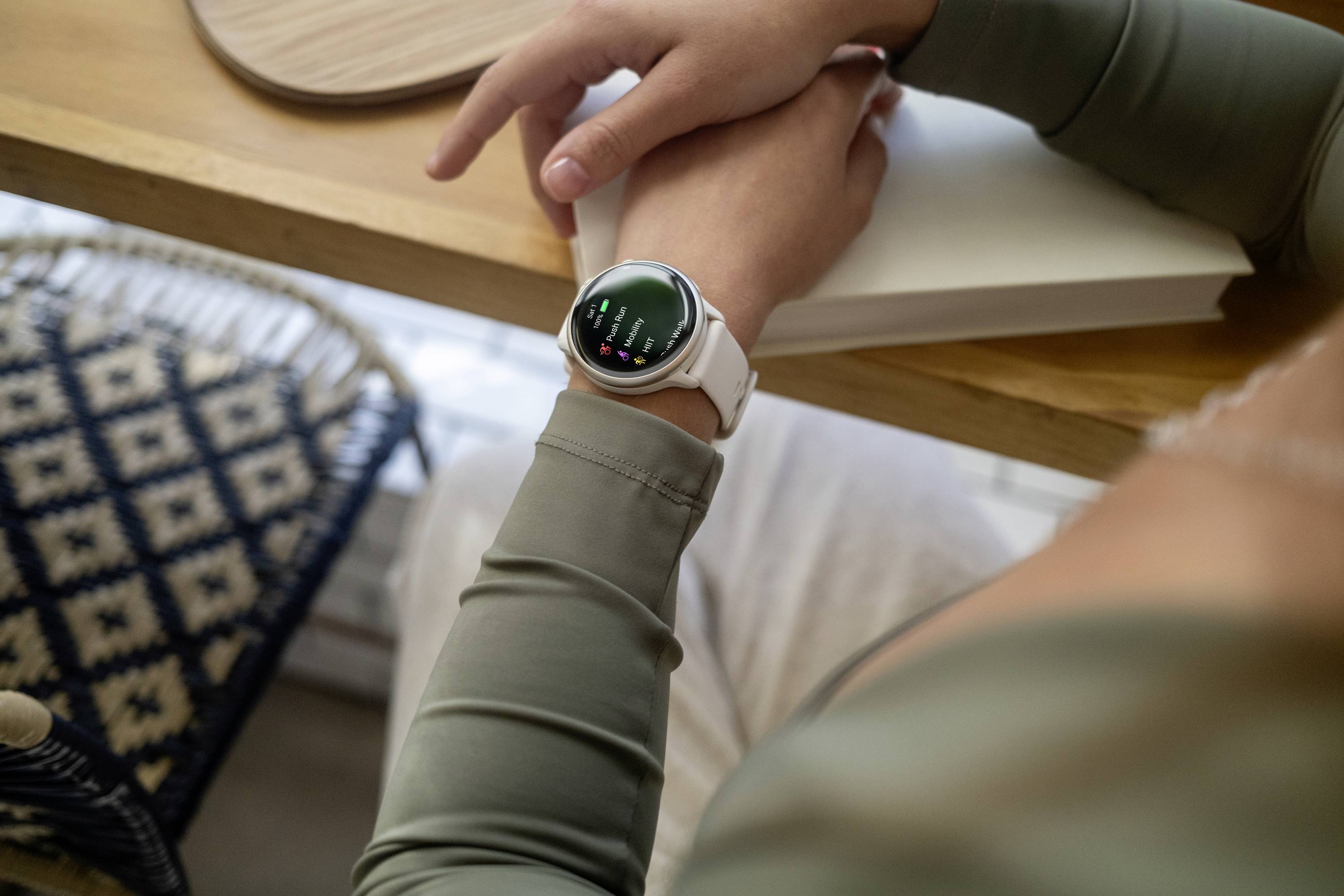 Eine Person mit einem Smartwatch am Handgelenk lehnt sich an einen Tisch. Die Uhr zeigt ein digitales Display an.
