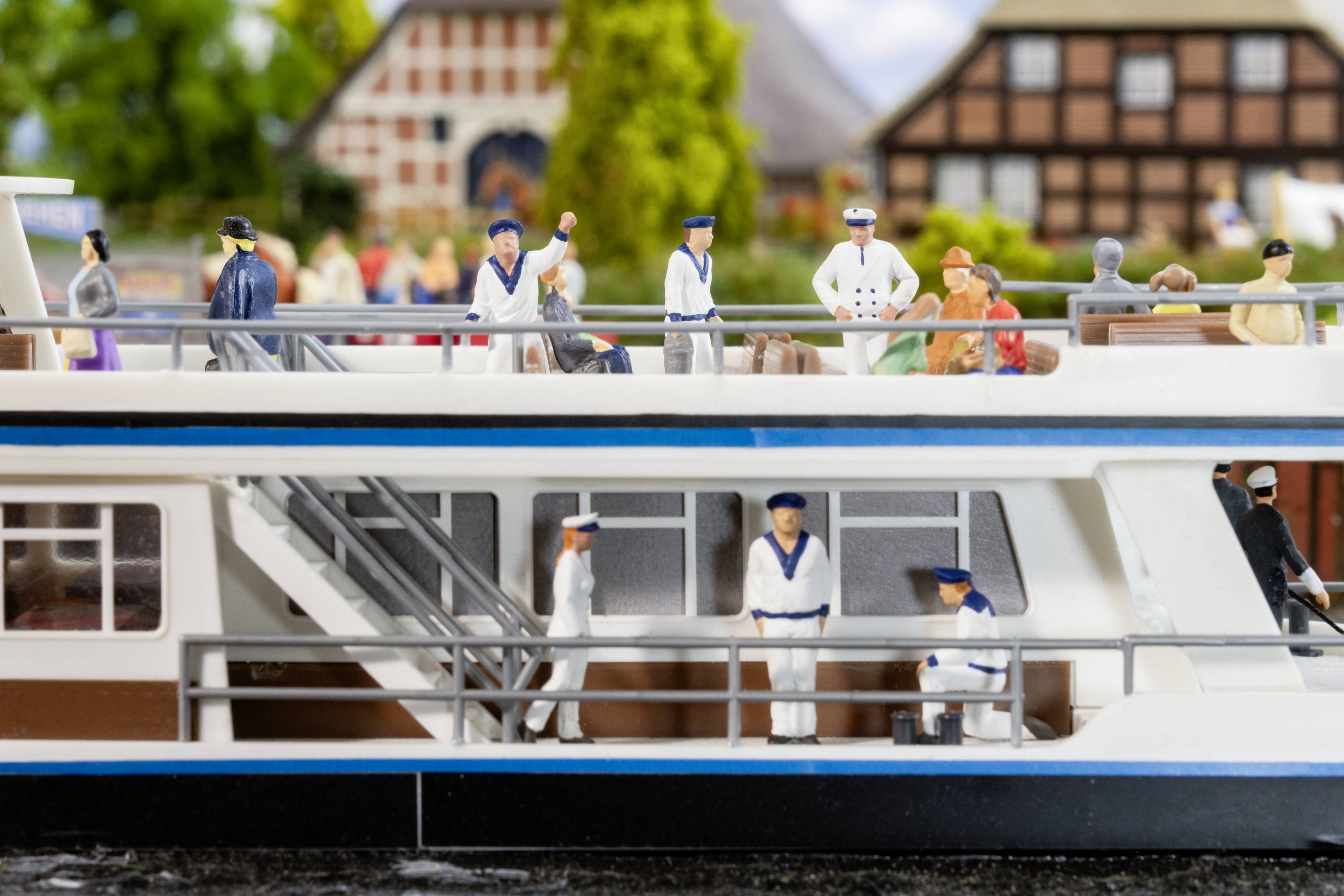Miniaturmodell eines zweistöckigen Ausflugsschiffs mit Figuren in Schiffsuniformen auf Deck. Im Hintergrund sind Fachwerkhäuser sichtbar.