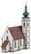 Modell einer Kirche mit grünem Kirchturm und spitzem Dach. Die Fassade ist weiß mit Backsteinverzierungen.