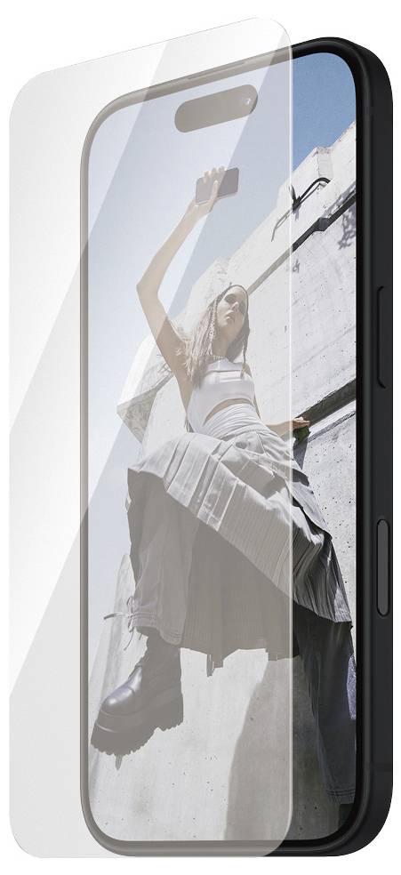 Eine Frau in modischer Kleidung posiert vor einer Betonwand, während sie Selfies mit einem Smartphone macht.