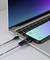 Ein Smartphone, das über ein USB-Kabel mit einem Laptop verbunden ist, wobei ein digitales Messgerät den Ladestrom anzeigt und Datenübertragung signalisiert.