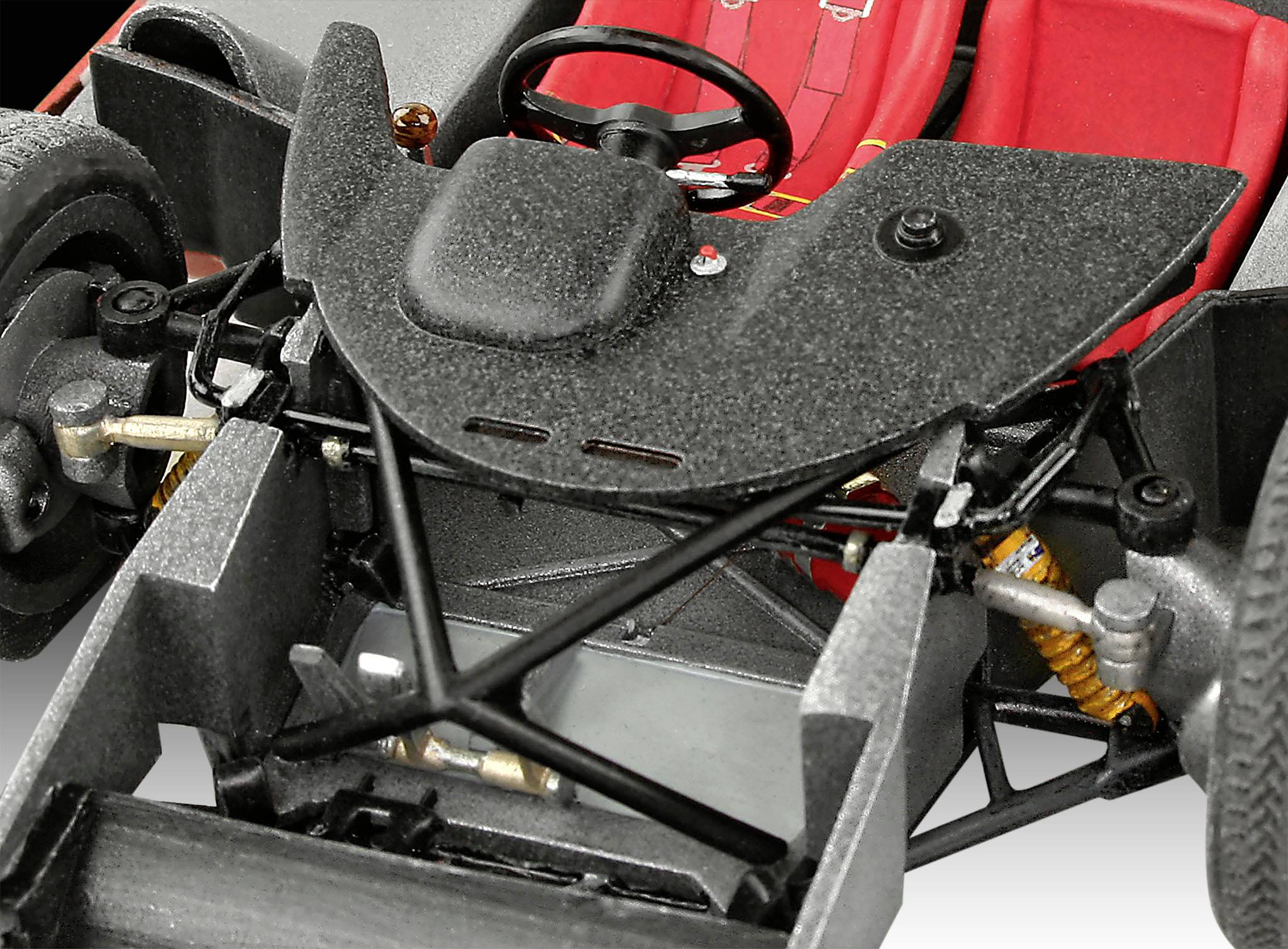 Nahaufnahme eines Modellauto-Chassis mit sichtbaren Federungen und einem roten Rennsitz im Hintergrund.