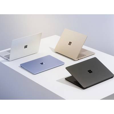 Vier Laptops in verschiedenen Farben (Weiß, Blau, Gold, Schwarz) werden auf einer weißen Oberfläche präsentiert und zeigen eine Vielfalt an Designs.