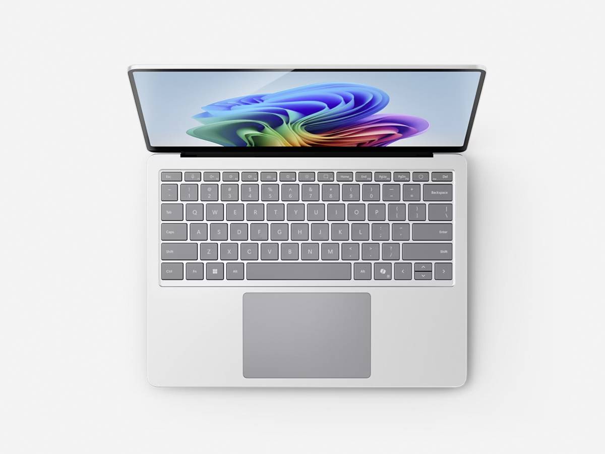 Ein silberner Laptop mit einem bunten abstrakten Design auf dem Bildschirm, von oben betrachtet, mit vollständiger Tastatur und Trackpad.