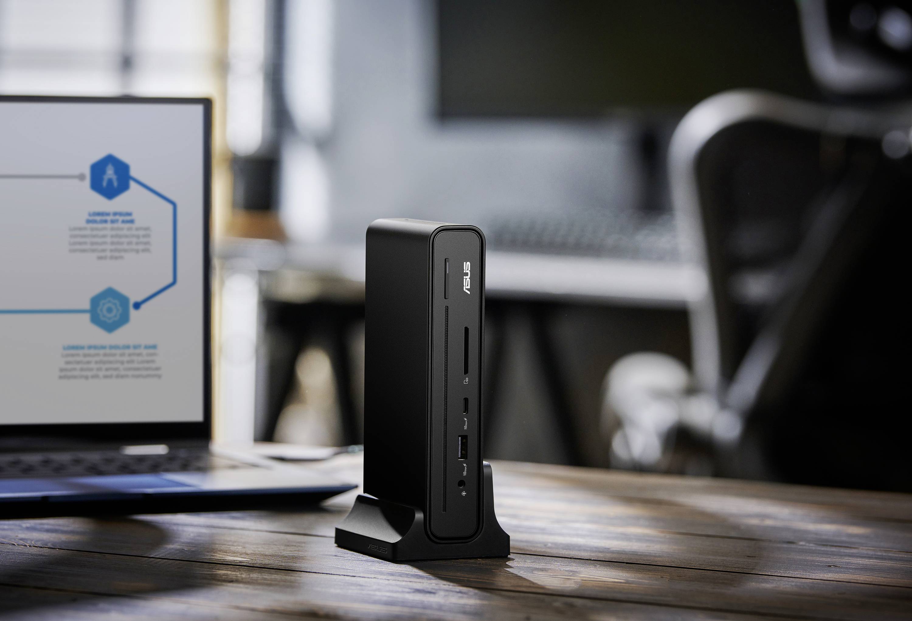Ein kompakter Computertower, der auf einem Holzschreibtisch neben einem geöffneten Laptop mit unscharfem Bildschirm und Grafiken steht, in einem modernen Büroumfeld.