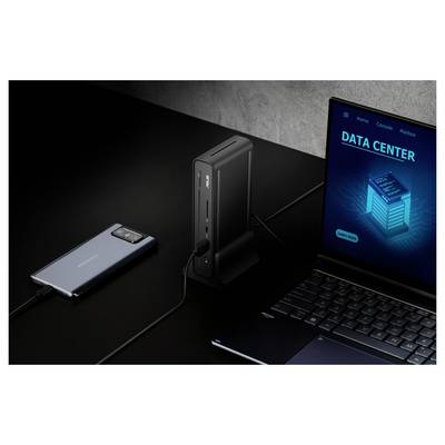 Ein Smartphone, das an einer Docking-Station neben einem Laptop angeschlossen ist, auf dem "DATA CENTER" auf dem Bildschirm angezeigt wird, alles auf einer dunklen Oberfläche.