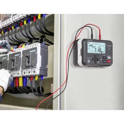 Ein Elektriker verwendet ein Multimeter, das mit einer Elektroverteilungsanlage verbunden ist, und misst Spannungs- und Stromstärkenwerte, um die Sicherheit der Ausrüstung zu gewährleisten.