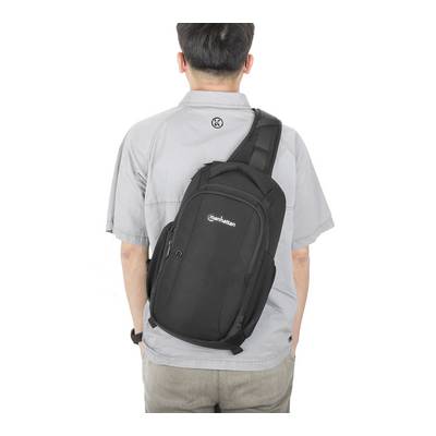 Mann von hinten mit grauem Hemd trägt einen schwarzen Rucksack über der linken Schulter.