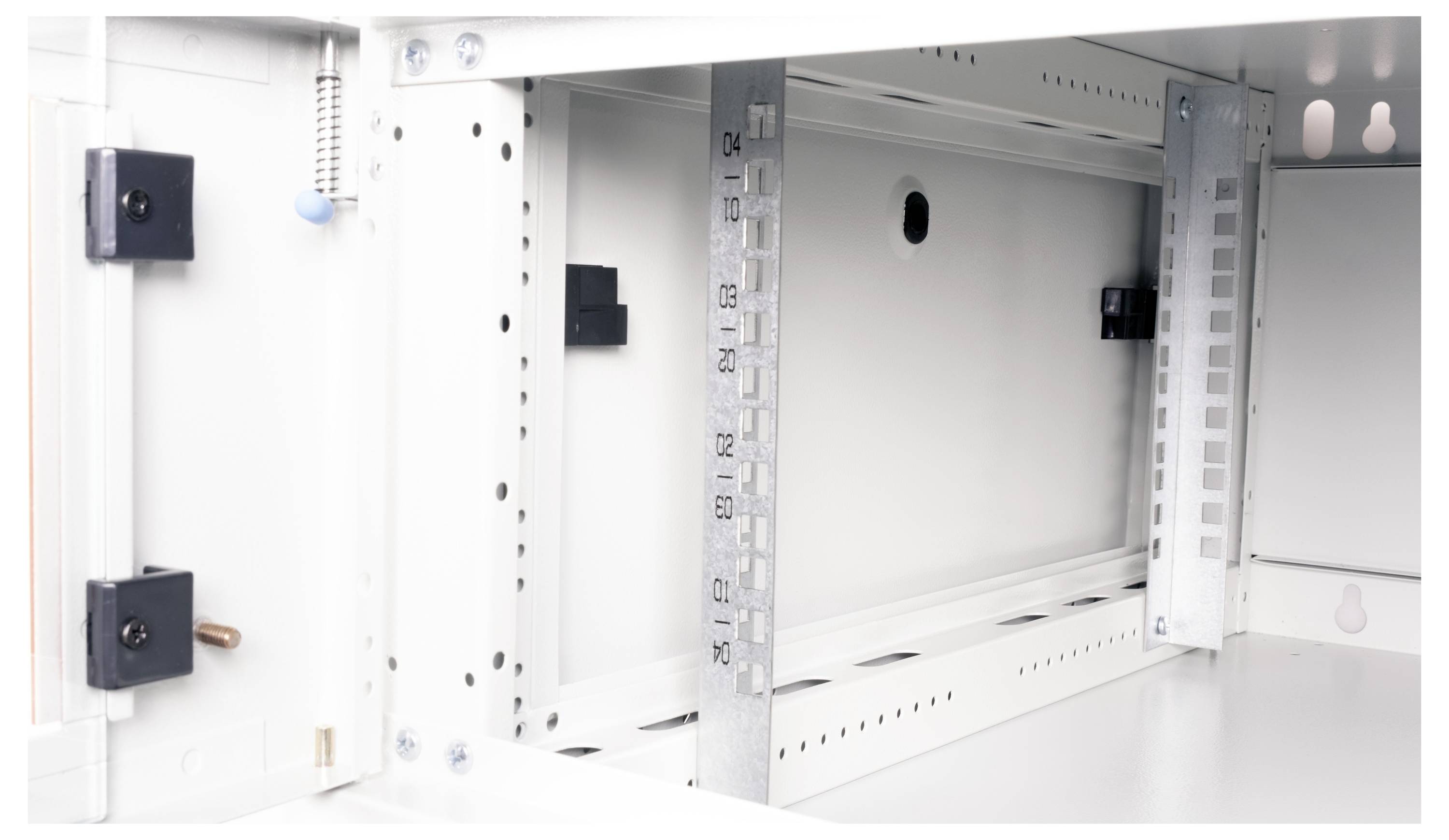 Innere Ansicht eines weißen Elektroverteilerkastens mit Befestigungshalterungen und gelochten Metallstreifen zur Kabelführung.