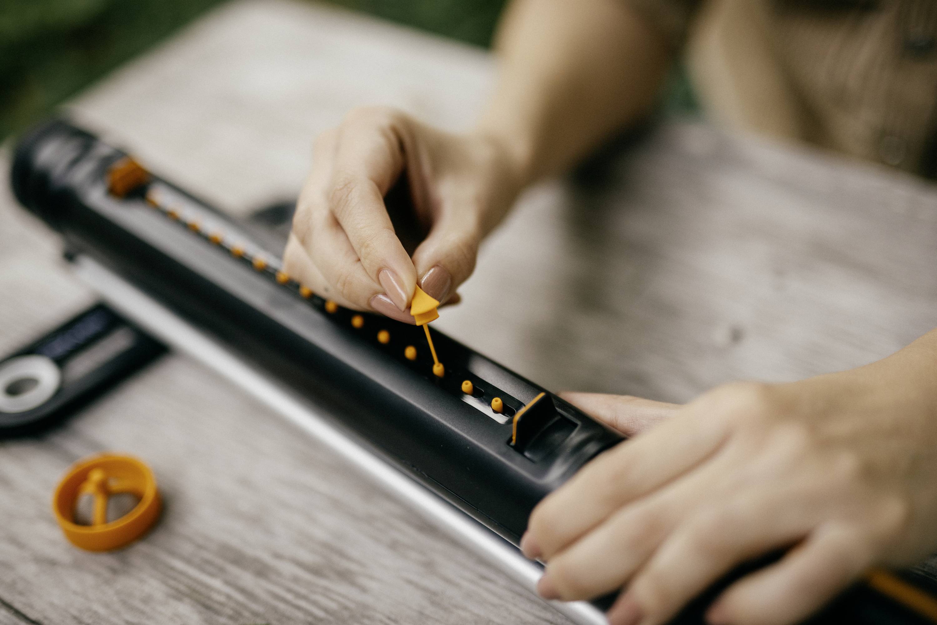 Eine Person ordnet orange Perlen auf einem schwarzen Abakus. Die Hände sind fokussiert, die Umgebung dezentralisiert.