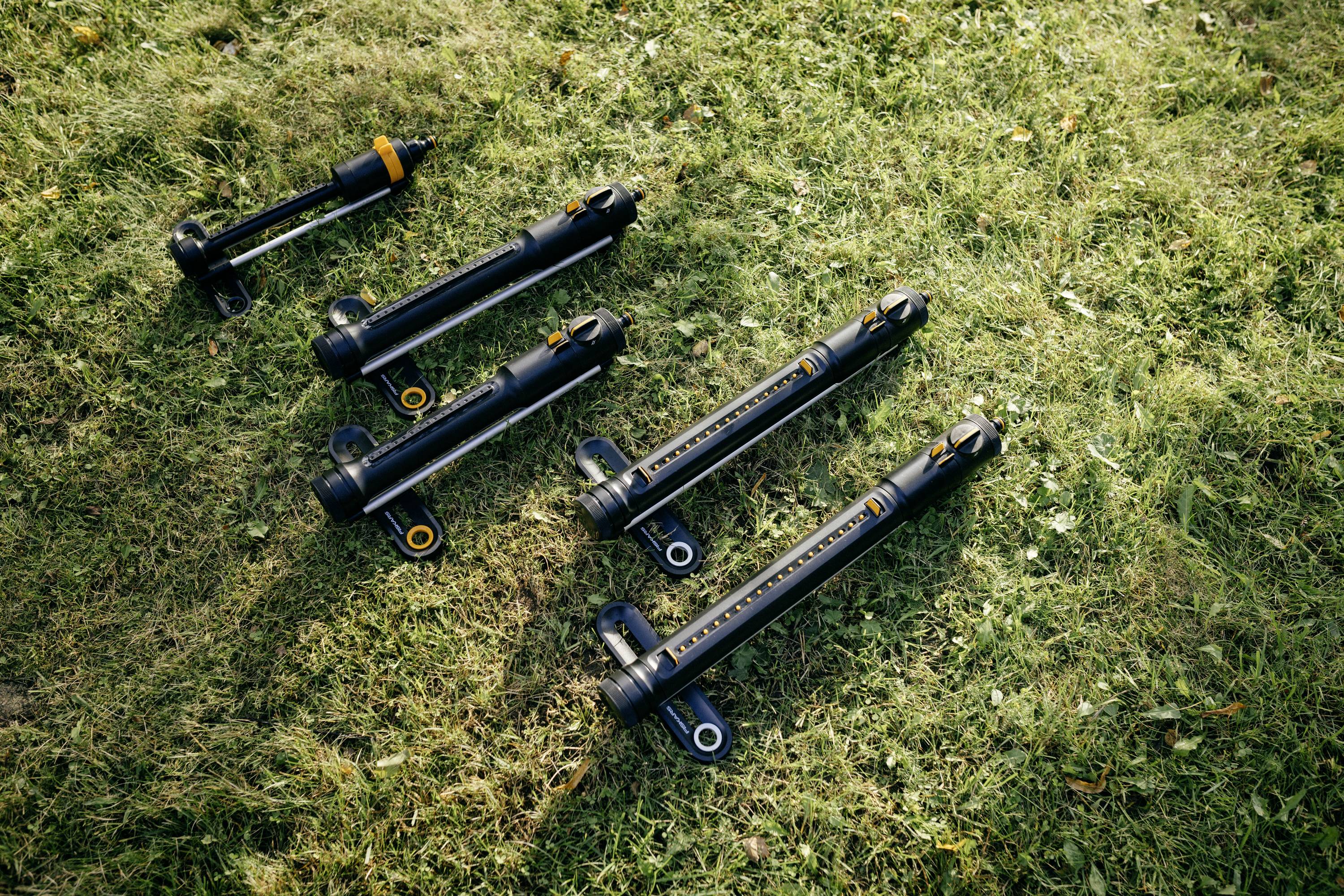 Sechs schwarze Stoßdämpfer liegen auf einer grünen Rasenfläche. Sie sind in unterschiedlichen Größen und haben orangene Akzente.