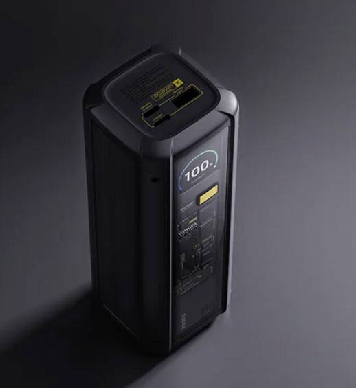 Ein hoher, schwarzer Powerbank zeigt '100%' Ladung auf seinem digitalen Display, was einen vollständig aufgeladenen Zustand repräsentiert, vor einem dunklen Hintergrund.