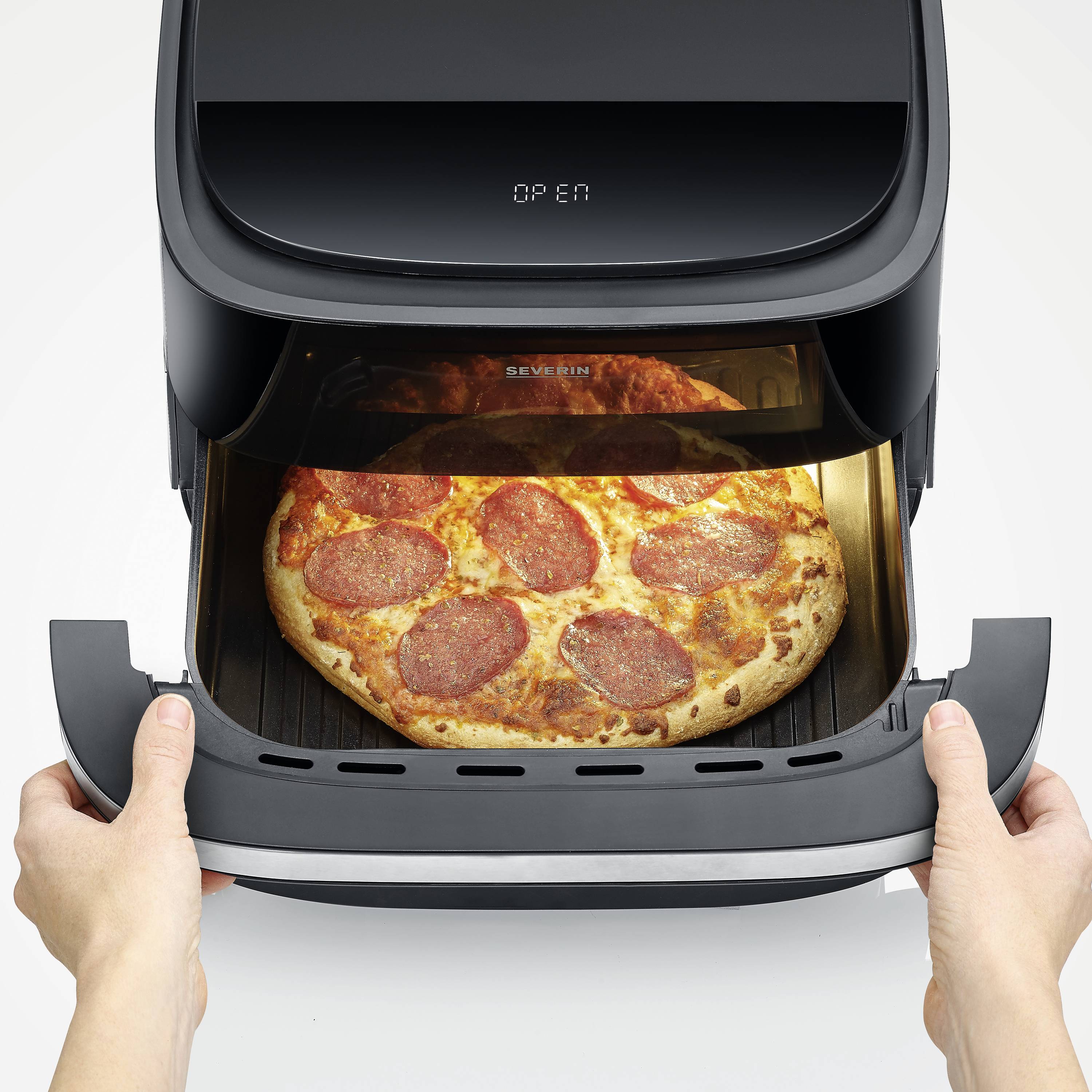 Eine Person entnimmt eine heiße Pepperoni-Pizza aus einem Luftfritteusengerät. Die Pizza ist goldbraun gebacken.