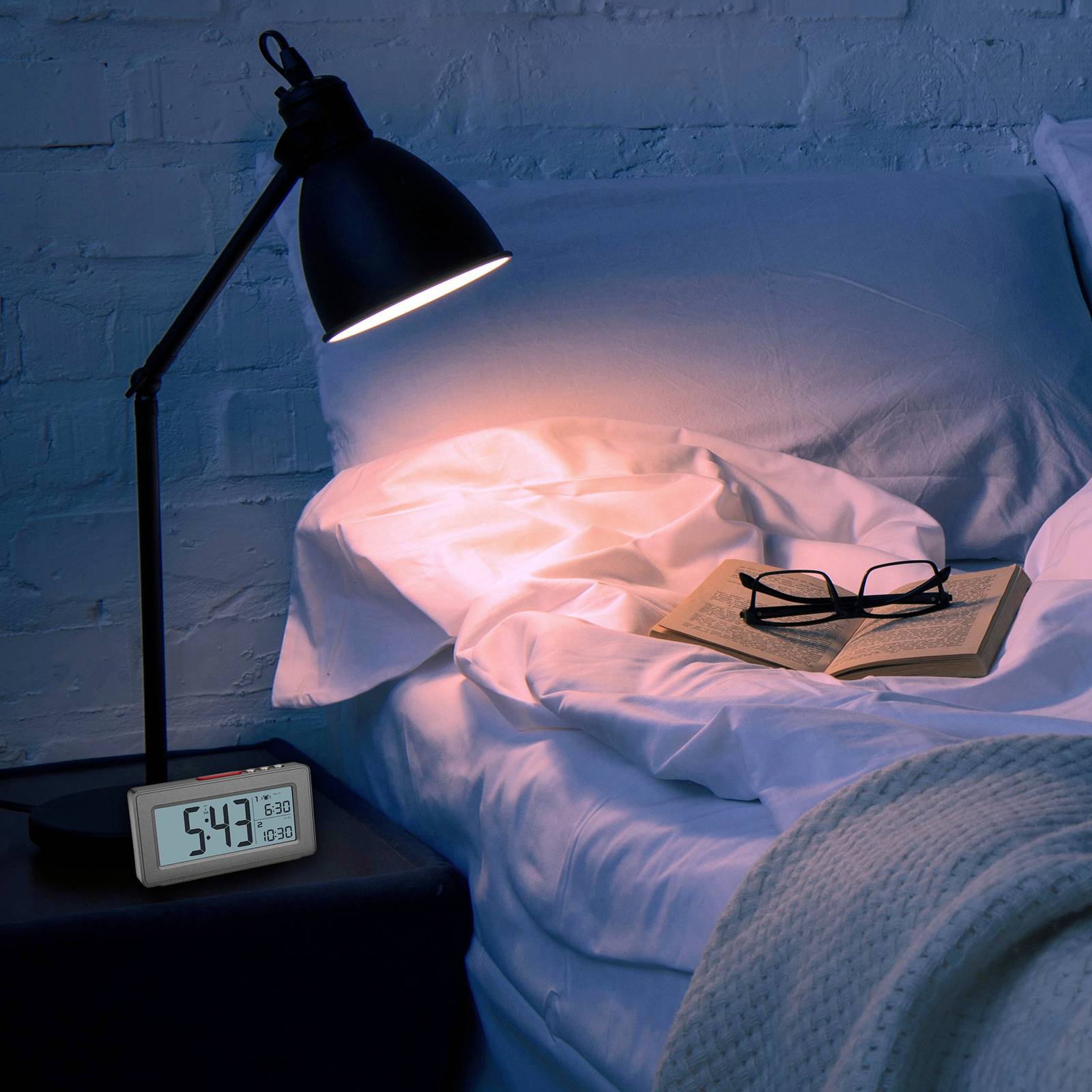 Nachttisch mit Wecker und Lampe, beleuchtet ein Buch und eine Brille auf einem ungemachten Bett, es ist 5:47 Uhr.