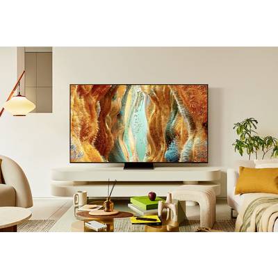 Ein modernes Wohnzimmer mit einem Flachbildfernseher, der ein abstraktes, buntes Kunstwerk zeigt. Im Raum sind stilvolle Möbel und Pflanzen.