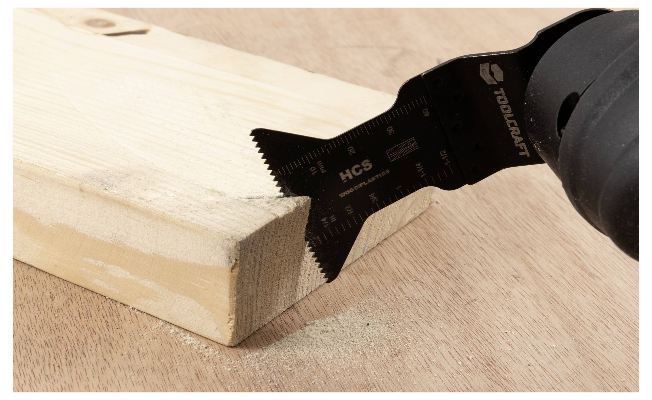 Eine Elektrowerkzeug mit einer Sägeblatt schneidet durch ein hellbraunes Holzstück auf einer Holzoberfläche. Staubpartikel sind sichtbar.