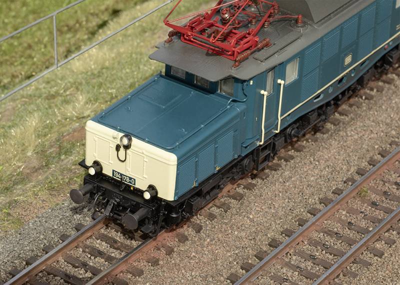 Eine detaillierte Modelllokomotive auf einem Gleis, umgeben von Gras. Die Lok hat eine blaue und cremefarbene Lackierung.