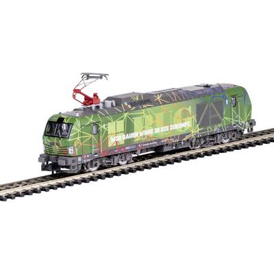 Eine grün-bunte Lokomotive mit Schriftzug 'Wir bauen Wege in die Zukunft', fährt auf einem Gleis, umgeben von geometrischen Mustern.