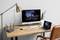 Ein Home-Office-Setup mit einem Desktop-Monitor und einem Laptop, die ein Orchester anzeigen, sowie einer Tastatur, Maus, Lampe und einer Pflanze auf einem Holzschreibtisch.