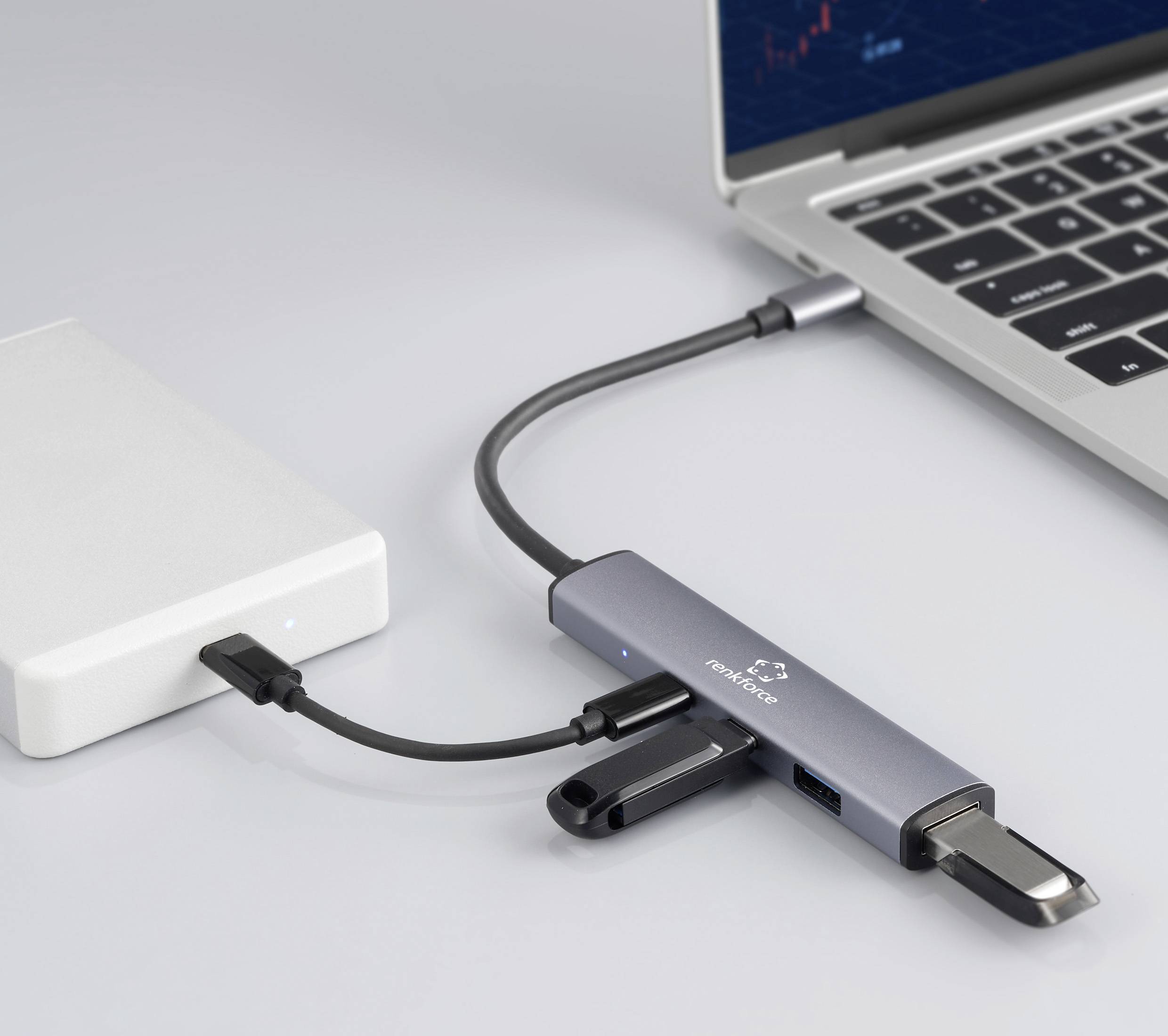 Ein Laptop, der mit einem Mehrfach-Hub verbunden ist, mit verschiedenen Geräten wie einer externen Festplatte und einem USB-Stick, was Datenübertragung veranschaulicht.